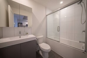 A modern bathroom with a shower, toilet, and vanity.