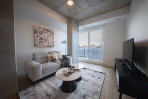 A modern living room with a sofa, coffee table, TV, and a large window.