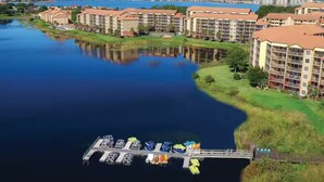 Un hotel frente al río con varias edificaciones, un muelle con barcos y un río tranquilo.