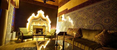 Una habitación con pared estampada, un sofá, una silla y un arco decorativo.