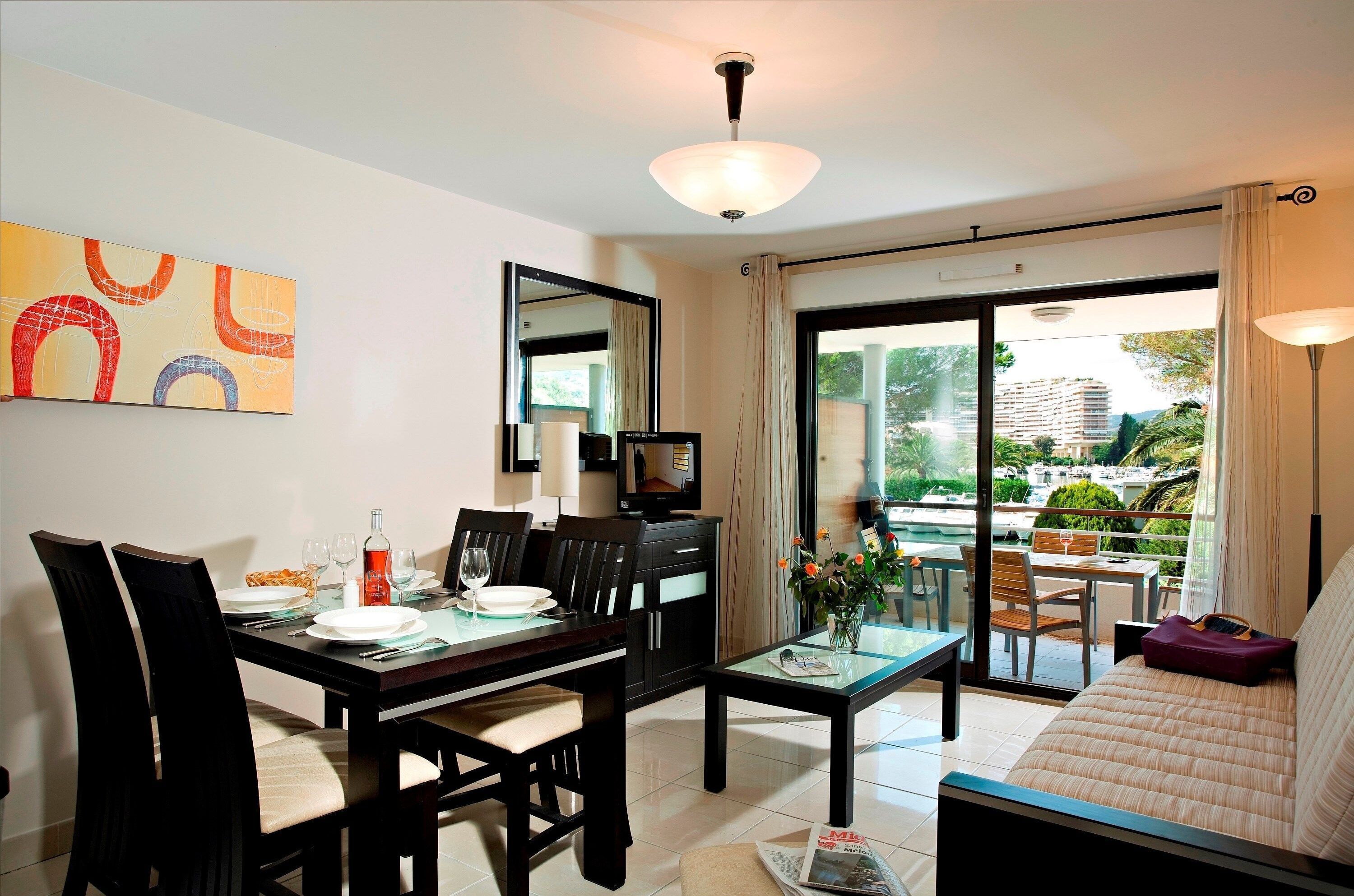 Un coin repas avec une table dressée pour quatre personnes, un canapé et un téléviseur.