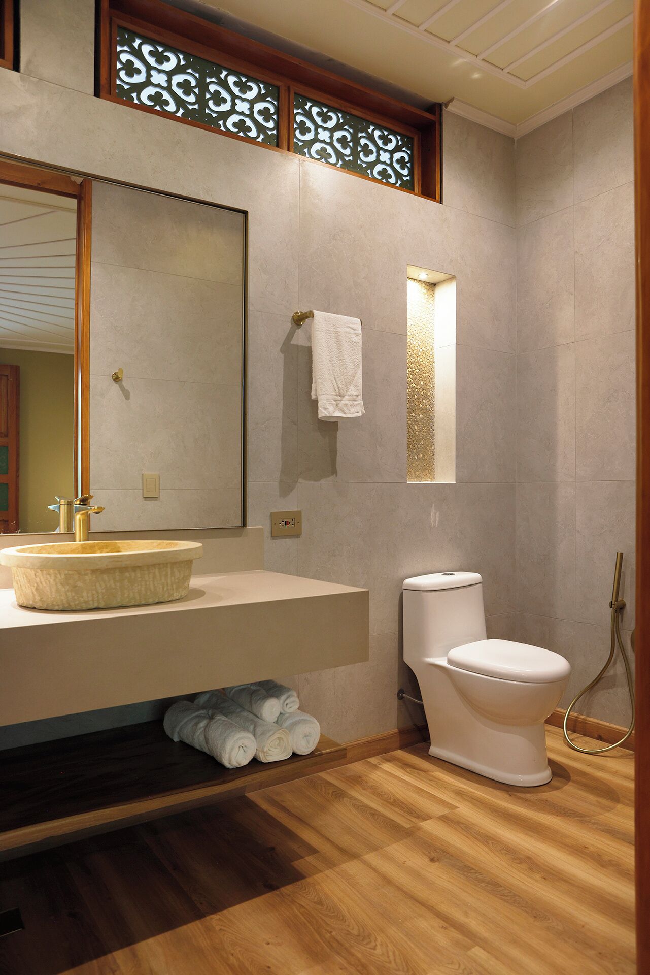 Un baño con tocador de madera, lavamanos, inodoro y zona de ducha.