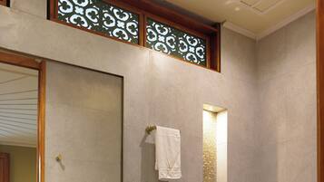 Un baño con tocador de madera, lavamanos, inodoro y zona de ducha.