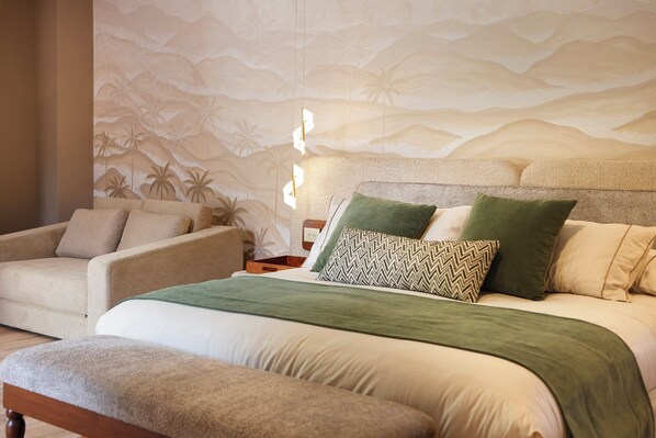 Um quarto com cama, cadeira e mesa de cabeceira.