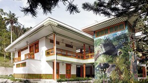 A two-story building with a balcony, a mural, and a garden. - El Molino Ecohotel (Salento)