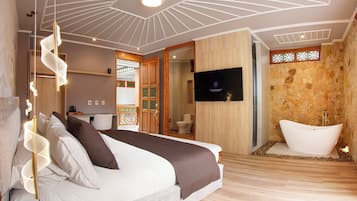 Een moderne slaapkamer met een bed, een televisie en een badkamer met een bad.