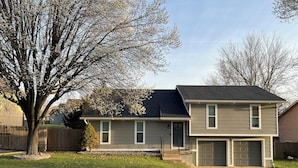 A two-story house with a garage, a front yard, and a large tree. - 4 bedrooms plus an outdoor entertainment area. World Cup ready! (Shawnee)