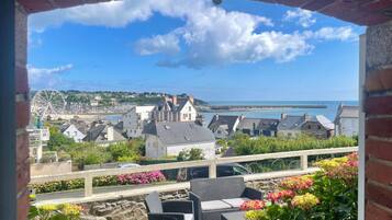 Une vue depuis un balcon donnant sur une ville côtière, avec ses bâtiments, sa jetée et sa grande roue.