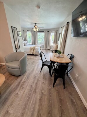 A modern bedroom with a bed, a ceiling fan, and a large window with curtains. - Stylish Studio—Pearl • Downtown • Ft Sam • UIW • Trinity • St. Mary’s • Parking (San Antonio)
