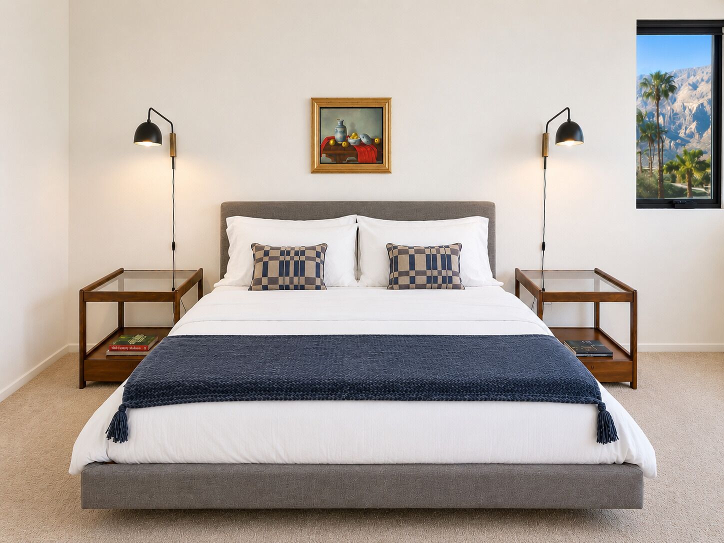 Ein ordentlich eingerichtetes Schlafzimmer mit einem großen Bett, zwei Nachttischen, einem gerahmten Bild an der Wand und einem Fenster mit Blick.