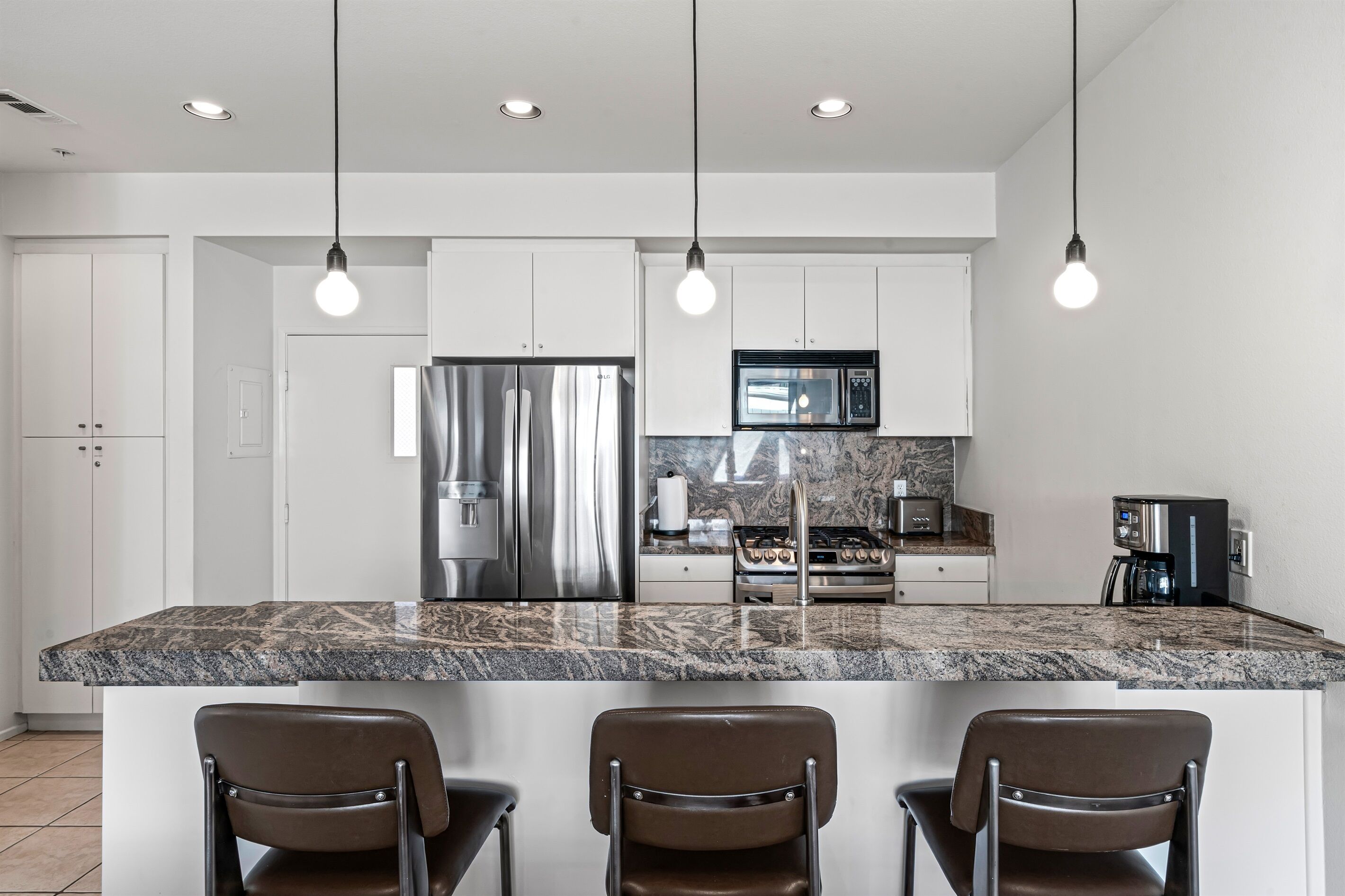 A modern kitchen with a large island, stainless steel appliances, and pendant lighting.