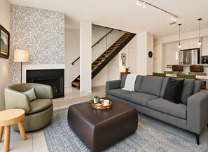 A modern living room with a sofa, ottoman, and a fireplace. - Downtown Modern Palm Springs Oasis | 2 King Suites (Palm Springs)