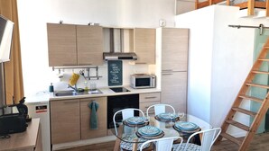 Una cucina compatta con elettrodomestici moderni, un tavolo da pranzo per quattro persone e una scala in legno.