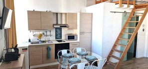 Una cucina compatta con elettrodomestici moderni, un tavolo da pranzo per quattro persone e una scala in legno.