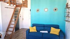 Una stanza con un letto a castello, una scala, un divano blu con cuscini gialli e specchi decorativi a parete.