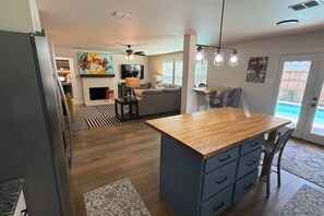 Eine moderne Küche mit einer Holzinsel, einem Essbereich mit Stühlen, einem Kamin und einem Wohnzimmer mit einer Couch.