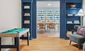 Una habitación con mesa de billar, un comedor con sillas y un sofá.
