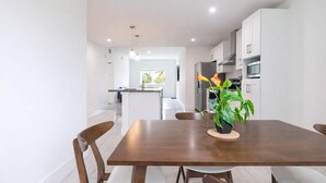 Una cocina moderna con armarios blancos, un refrigerador de acero inoxidable y un microondas.