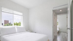 Un dormitorio con una cama grande, una mesita de noche y una ventana con persianas.
