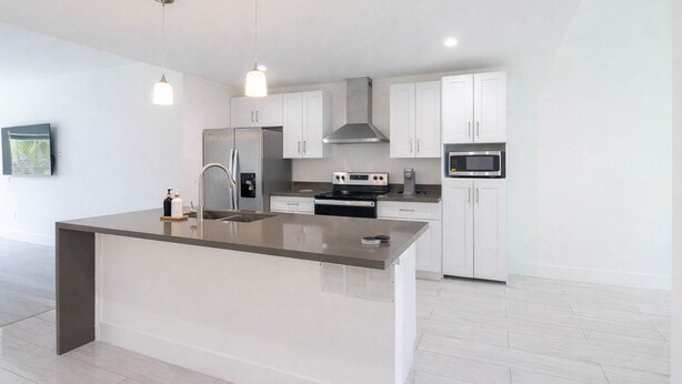 Una cocina moderna con una isla central, electrodomésticos de acero inoxidable e iluminación colgante.