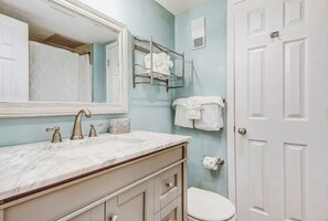 Ein Badezimmer mit Marmorwaschbecken, einem großen Spiegel, einem Handtuchhalter und einer Toilette.