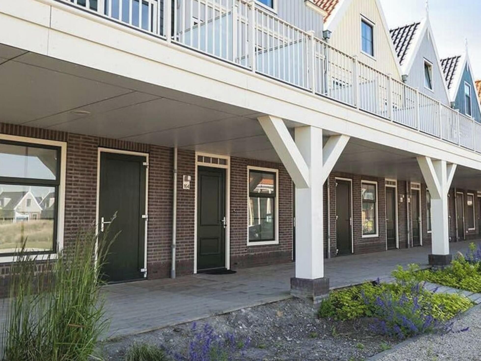 Een gebouw met een overdekte galerij, meerdere deuren en een bakstenen gevel.