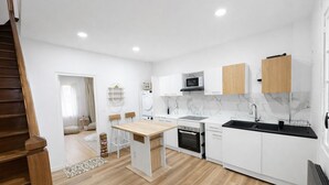 Eine moderne Küche mit weißen Schränken, einem Holzespeisetisch und einem eingebauten Backofen.