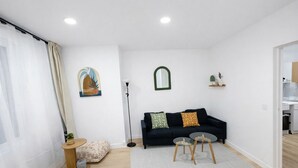Ein Wohnzimmer mit einer Couch, zwei Beistelltischen, einer Stehlampe und einem Bild an der Wand.
