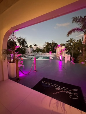 Un área de piscina con tumbonas, piscina y palmeras.