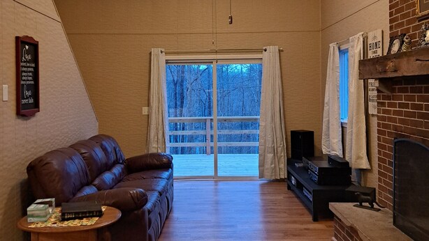 Un salon spacieux doté d’un ventilateur de plafond, d’un canapé en cuir, d’une petite table d’appoint, d’une cheminée et d’une grande porte-fenêtre coulissante donnant sur une terrasse.