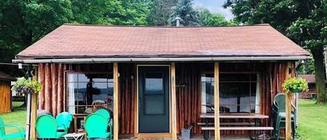 A rustic cabin with a porch, wooden exterior, and outdoor seating area.