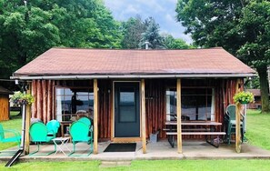 Eine rustikale Holzhütte mit Veranda, Holzfassade und einer Sitzgelegenheit im Freien.