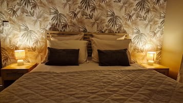 A bed with a quilted cover, two bedside lamps, and a wall with a leaf pattern.