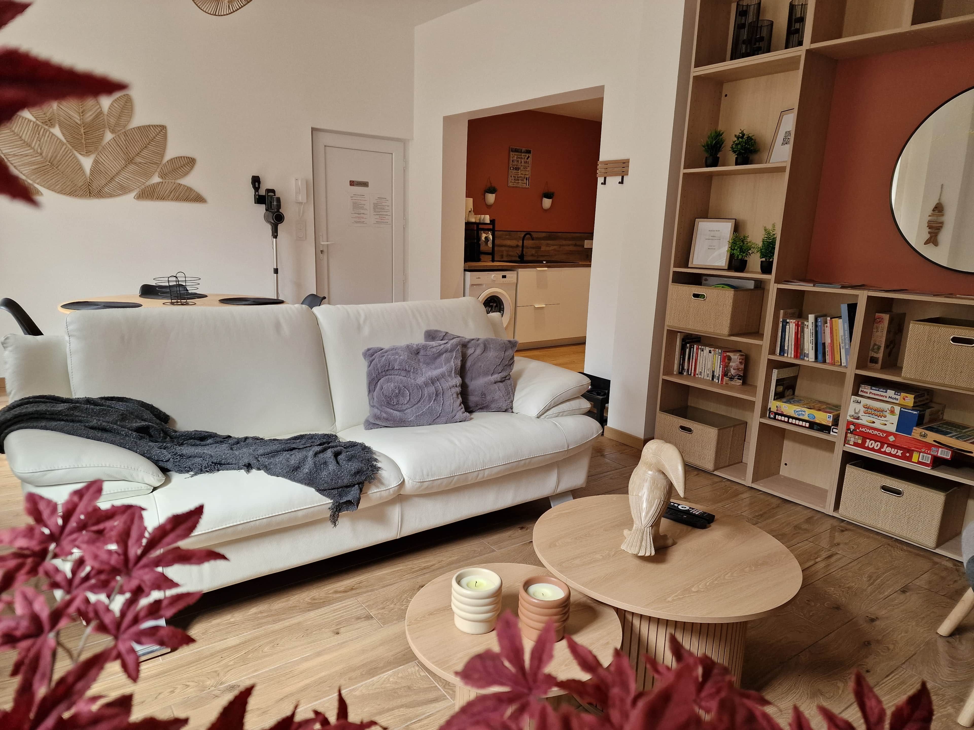 A modern living room with a white sofa, a round coffee table, and a bookshelf filled with books and board games.