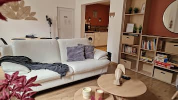 A modern living room with a white sofa, a round coffee table, and a bookshelf filled with books and board games.