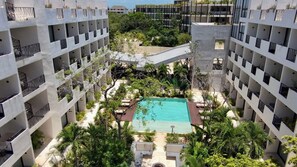 A hotel with a central swimming pool surrounded by lush greenery and multiple balconies. - Family Pent-House with luxury amenities (Tulum)