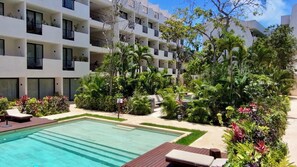 A modern building with multiple balconies, a swimming pool, and lush greenery. - Family Pent-House with luxury amenities (Tulum)