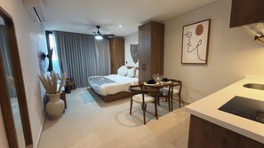 A modern hotel room with a bed, a dining table with chairs, a kitchenette, and a ceiling fan. - Family Pent-House with luxury amenities (Tulum)