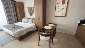 A bedroom with a bed, bedside table, chairs, a wooden wardrobe, and a wall art piece. - Family Pent-House with luxury amenities (Tulum)