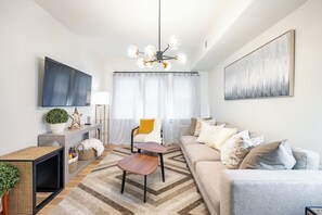Ein modernes Wohnzimmer mit einer Couch, einem Couchtisch, einem Fernseher und Kunstwerken.