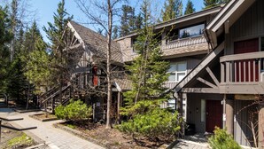 A multi-story building with a wooden facade, a staircase leading to the entrance, and a red door. - Steller's Jay Chalet - private hot tub, ski in/out, 2 bedroom, 2 bath townhome (Whistler)
