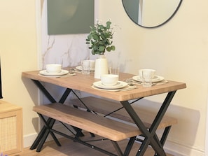 A dining table with white plates, bowls, and glasses, a vase with green foliage, and a mirror on the wall. - Large 3 bed house, 4 TVs, driveway parking. (Newcastle upon Tyne)