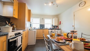 A modern kitchen with a stove, oven, and dining table set for breakfast.