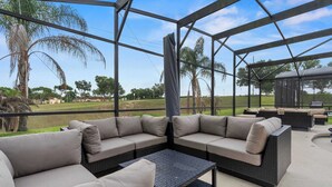 Un área de estar techada al aire libre con muebles de mimbre y vistas del paisaje circundante.