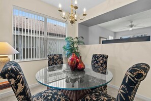 Dining area with a glass table, patterned chairs, and a brass chandelier. - 4BR retreat w/ screened pool & spa (Davenport)