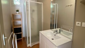 Ein Badezimmer mit Waschbecken, Spiegel und Duschkabine.
