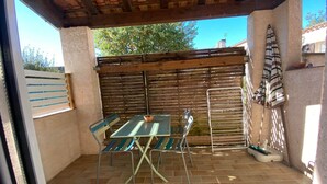Eine Terrasse im Freien mit Tisch und Stühlen, einem Holzzaun und einem gefliesten Boden.