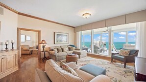 Ein geräumiges Wohnzimmer mit großem Fenster und Blick auf das Meer und Gebäude, inklusive Kamin und Essbereich.