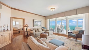 Ein geräumiges Wohnzimmer mit großem Fenster und Blick auf das Meer und Gebäude, inklusive Kamin und Essbereich.
