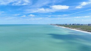 Eine Küstenansicht mit blauem Himmel, Sandstrand und einer Reihe von Gebäuden entlang der Küste.